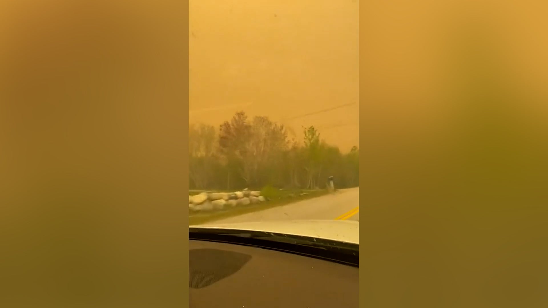 Orange haze from Canada wildfires engulfs road